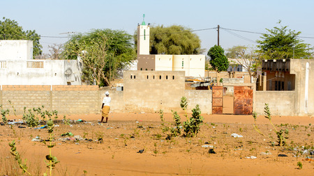 ROAD TO LAMPOUL, SENEGAL - APR 23, 2017: Unidentified Senegalese woman in white shirt and headscarf stands from behind. Still many people in Senegal live in povertyのeditorial素材
