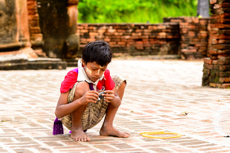 INWA, MYANMAR - AUG 25, 2016: Unidentified Burmese young boy plays on the ground. 68 per cent of ...
