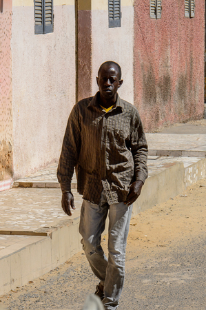 SAINT LOUIS, SENEGAL - APR 24, 2017: Unidentified Senegalese man walks along the road in Saint Louis, one of the biggest cities in Senegalのeditorial素材