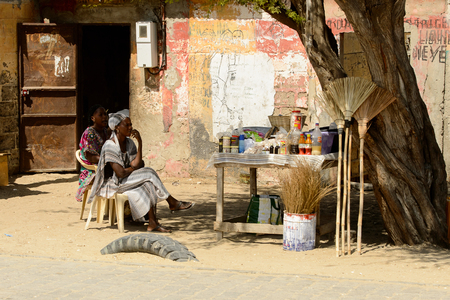 ROAD TO LAMPOUL, SENEGAL - APR 23, 2017: Unidentified Senegalese women sell goods on the street near the tree. Still many people in Senegal live in povertyのeditorial素材