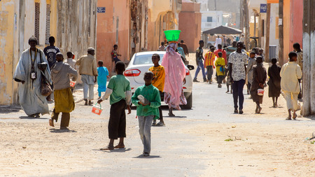 SAINT LOUIS, SENEGAL - APR 24, 2017: Unidentified Senegalese people walk along the road between...