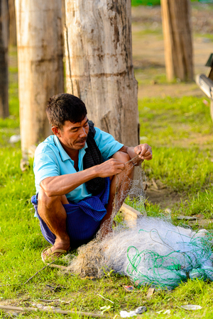 TAUNGTHAMAN LAKE, MYANMAR - AUG 25, 2016: Unidentified Burmese fisherman prepares a net, Taungthaman Lake near Amarapura, the former capital of Myanmarのeditorial素材