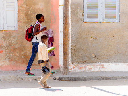 SAINT LOUIS, SENEGAL - APR 24, 2017: Unidentified Senegalese little boy walks beside the road and reads a book in Saint Louis, one of the biggest cities in Senegalのeditorial素材