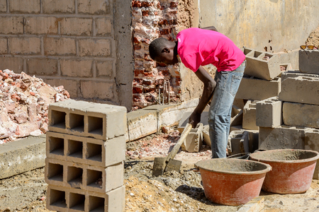 SAINT LOUIS, SENEGAL - APR 24, 2017: Unidentified Senegalese boy in pink shirt digs the ground with a help of shovel in Saint Louis, one of the biggest cities in Senegalのeditorial素材