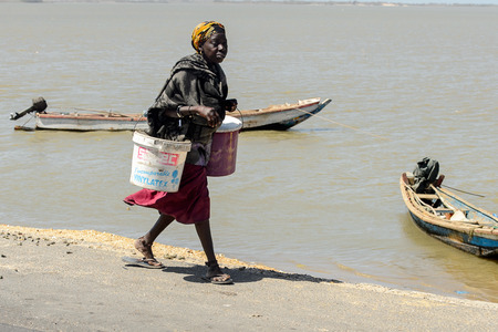 ROAD TO LAMPOUL, SENEGAL - APR 23, 2017: Unidentified Senegalese woman carries two buckets on the...