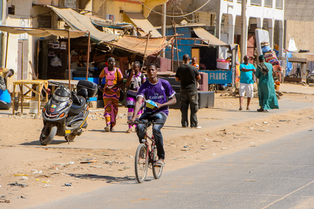 SAINT LOUIS, SENEGAL - APR 24, 2017: Unidentified Senegalese boy rides a bicycle in Saint Louis, one of the biggest cities in Senegalのeditorial素材