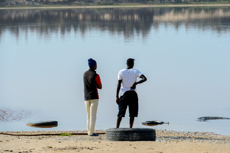 LAC ROSE, SENEGAL - APR 26, 2017: Unidentified Senegalese two men stand on the salty coast of the Lake Retba, UNESCO World Heritage Siteのeditorial素材