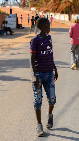 LAC ROSE reg., SENEGAL - APR 26, 2017: Unidentified Senegalese boy in violet shirt walks in a village.のeditorial素材