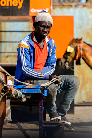 KAYAR, SENEGAL - APR 27, 2017: Unidentified Senegalese man sits on the cart in the street of Kayar, Senegal.のeditorial素材