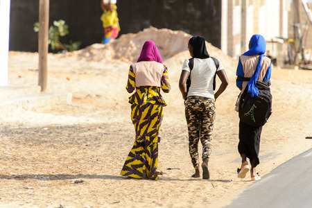 KAYAR, SENEGAL - APR 27, 2017: Unidentified Senegalese three women in headscarves walk beside the road  in the street of Kayar, Senegal.のeditorial素材