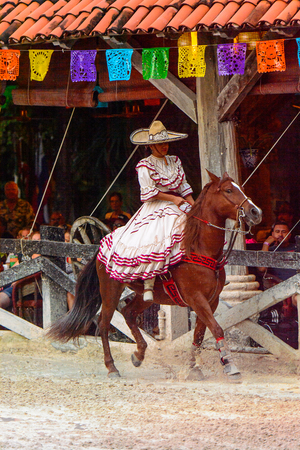 XCARET, MEXICO - NOV 7, 2016: Unidentified Mexican cowgirl in national dress rides a horse in the Xcaret park, Mexiocのeditorial素材