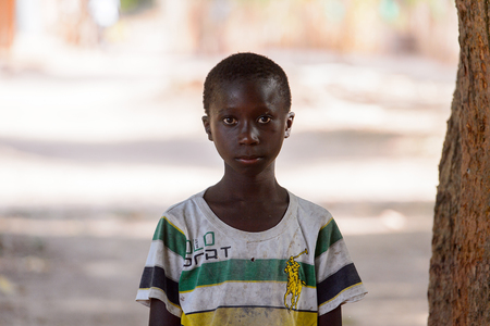 OUSSOUYE, SENEGAL - APR 30, 2017: Unidentified Senegalese  little boy in dirty shirt stands in the Sacred Forest near Kaguit villageのeditorial素材