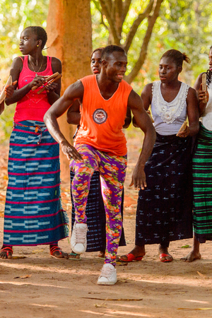 Kaguit vil., SENEGAL - APR 30, 2017: Unidentified Diola man in orange shirt and colored pants moves during a traditional dance Kumpo in a Sacred Forest near Kaguit villageのeditorial素材