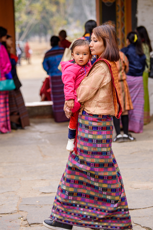 TRIMPHU, BHUTAN - MAR 8, 2017: Unidentified Ngalops woman carries a baby. Ngalops is one of the most populous ethnic groups of Bhutanのeditorial素材