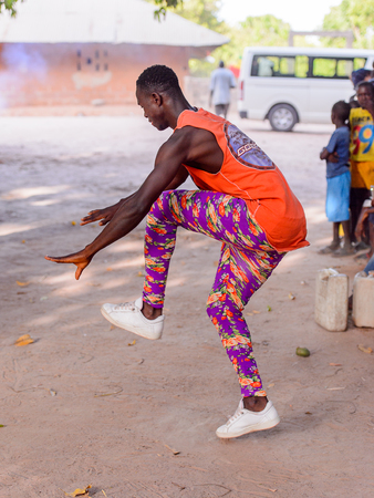 Kaguit vil., SENEGAL - APR 30, 2017: Unidentified Diola man in orange shirt and colored pants moves during a traditional dance Kumpo in a Sacred Forest near Kaguit villageのeditorial素材
