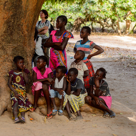 OUSSOUYE, SENEGAL - APR 30, 2017: Unidentified Senegalese little boys and girls sit around the street in the Sacred Forest near Kaguit villageのeditorial素材