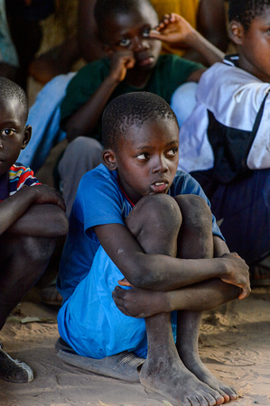 OUSSOUYE, SENEGAL - APR 30, 2017: Unidentified Senegalese group of little boys sit on the ground and watch the show in the Sacred Forest near Kaguit villageのeditorial素材