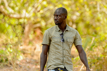 ROAD TO BISSAU, GUINEA B. - MAY 1, 2017: Unidentified local man in a shirt walks in a village in Guinea Bissau. Still many people in the country live in povertyのeditorial素材