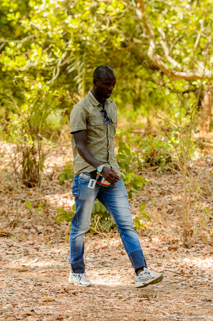 ROAD TO BISSAU, GUINEA B. - MAY 1, 2017: Unidentified local man walks along the pathway in a village in Guinea Bissau. Still many people in the country live in povertyのeditorial素材