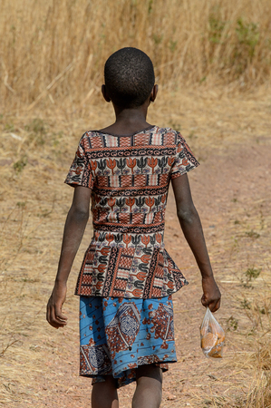 KOUTAMMAKOU, TOGO - JAN 13, 2017: Unidentified Togolese little girl walks in the village. Togo children suffer of poverty due to the bad economy.のeditorial素材