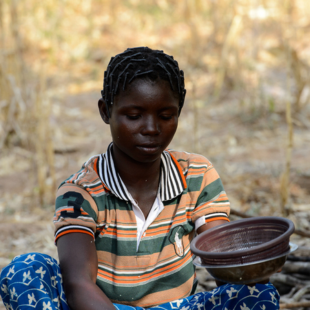 KOUTAMMAKOU, TOGO - JAN 13, 2017: Unidentified Togolese  woman holds a bowl in the village. Togo people suffer of poverty due to the bad economy.のeditorial素材