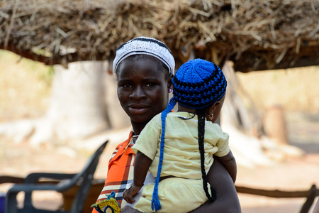 KOUTAMMAKOU, TOGO - JAN 13, 2017: Unidentified Togolese  woman carries a baby in the village. Togo people suffer of poverty due to the bad economy.のeditorial素材