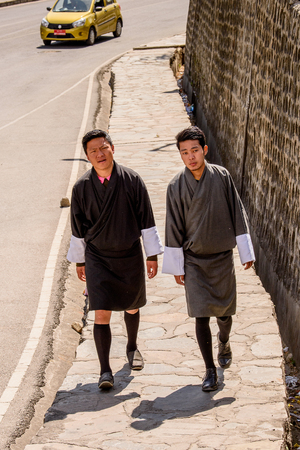 TRIMPHU, BHUTAN - MAR 8, 2017: Unidentified Ngalops boys in traditional clothes walk along the road. Ngalops is one of the most populous ethnic groups of Bhutanのeditorial素材