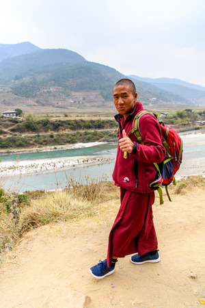 TRIMPHU, BHUTAN - MAR 8, 2017: Unidentified Ngalops boy in red clothes walks along the road. Ngalops is one of the most populous ethnic groups of Bhutanのeditorial素材