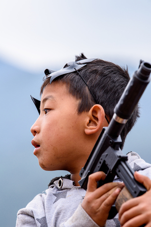 TRIMPHU, BHUTAN - MAR 8, 2017: Unidentified Ngalops little boy plays with a gun. Ngalops is one of the most populous ethnic groups of Bhutanのeditorial素材