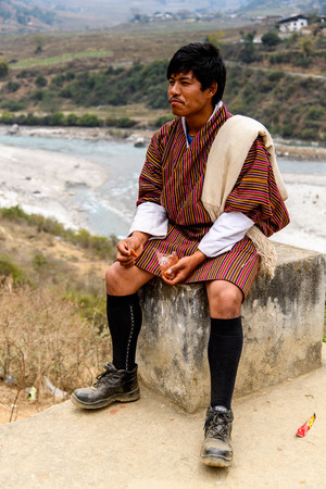TRIMPHU, BHUTAN - MAR 8, 2017: Unidentified Ngalops man sits on the stone. Ngalops is one of the most populous ethnic groups of Bhutanのeditorial素材