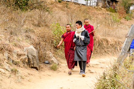 TRIMPHU, BHUTAN - MAR 8, 2017: Unidentified Ngalops boys in traditional clothes walk along the street. Ngalops is one of the most populous ethnic groups of Bhutanのeditorial素材
