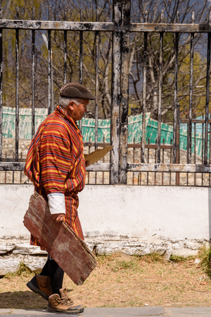 TRIMPHU, BHUTAN - MAR 8, 2017: Unidentified Ngalops old man walks on the street with a piece of wood. Ngalops is one of the most populous ethnic groups of Bhutanのeditorial素材