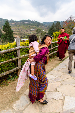 TRIMPHU, BHUTAN - MAR 8, 2017: Unidentified Ngalops woman carries a baby. Ngalops is one of the most populous ethnic groups of Bhutanのeditorial素材