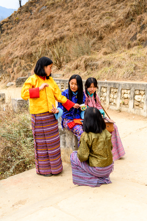 TRIMPHU, BHUTAN - MAR 8, 2017: Unidentified Ngalops girls walk on the bridge. Ngalops is one of the most populous ethnic groups of Bhutanのeditorial素材