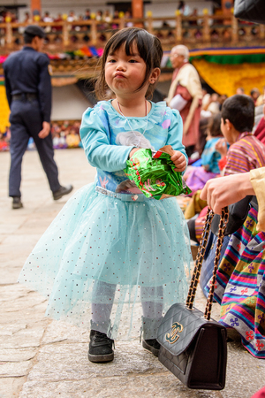 TRIMPHU, BHUTAN - MAR 8, 2017: Unidentified Ngalops little girl eats something. Ngalops is one of the most populous ethnic groups of Bhutanのeditorial素材