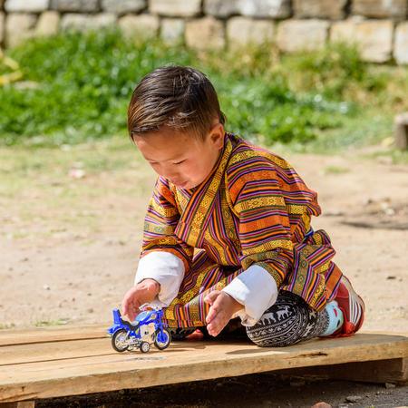 TRIMPHU, BHUTAN - MAR 8, 2017: Unidentified Ngalops little boy plays with a tiny motorcycle. Ngalops is one of the most populous ethnic groups of Bhutanのeditorial素材
