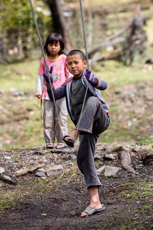 TRIMPHU, BHUTAN - MAR 8, 2017: Unidentified Ngalops little boy holds a swing. Ngalops is one of the most populous ethnic groups of Bhutanのeditorial素材