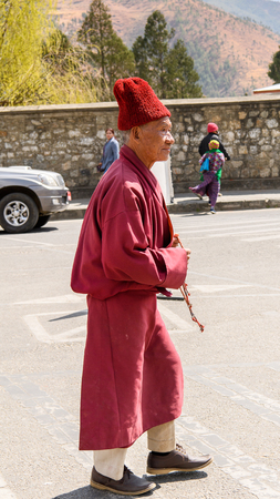TRIMPHU, BHUTAN - MAR 8, 2017: Unidentified Ngalops man in traditional clothes walks on the street with beads. Ngalops is one of the most populous ethnic groups of Bhutanのeditorial素材