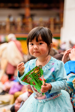 TRIMPHU, BHUTAN - MAR 8, 2017: Unidentified Ngalops little girl eats something. Ngalops is one of the most populous ethnic groups of Bhutanのeditorial素材