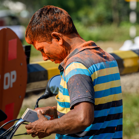SIKKIM, INDIA - MAR 13, 2017: Unidentified Indian man in striped shirt sits from behind with painted clothes and hair during the Holi day, the Celebration of Springのeditorial素材