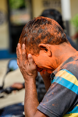 SIKKIM, INDIA - MAR 13, 2017: Unidentified Indian painted man puts his hands on his head during the Holi day, the Celebration of Springのeditorial素材