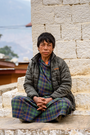 TRIMPHU, BHUTAN - MAR 8, 2017: Unidentified Ngalops man in plaid clothes sits in a temple. Ngalops is one of the most populous ethnic groups of Bhutanのeditorial素材