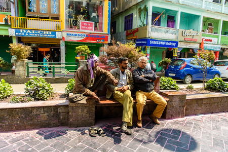 SIKKIM, INDIA - MAR 13, 2017: Unidentified Indian three men rest on the bench near the flowerbed full of bushes.のeditorial素材