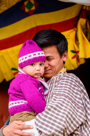 TRIMPHU, BHUTAN - MAR 8, 2017: Unidentified Ngalops man carries a baby. Ngalops is one of the most populous ethnic groups of Bhutanのeditorial素材