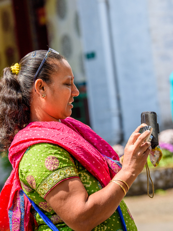 SIKKIM, INDIA - MAR 13, 2017: Unidentified Indian woman with pony tail wears traditional clothes and holds a camera in her hands.のeditorial素材
