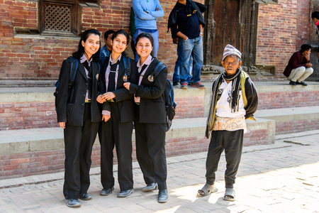 KATMANDU, NEPAL - MAR 6, 2017: Unidentified Chhetri three girls in suits with backpacks smile. Chhetris is the most populous ethnic group of Nepalのeditorial素材