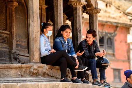 KATMANDU, NEPAL - MAR 6, 2017: Unidentified Chhetri people sit on the street near the colums....