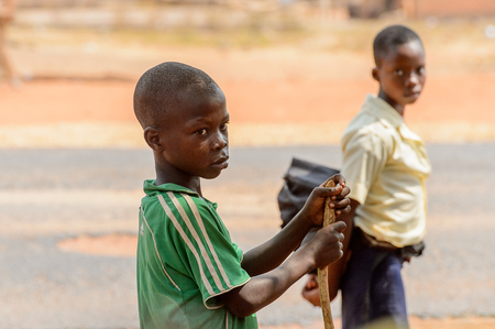 PIRA, BENIN - JAN 12, 2017: Unidentified Beninese little boy in green shirt with stripes looks ahead. Benin children suffer of poverty due to the bad economy.のeditorial素材