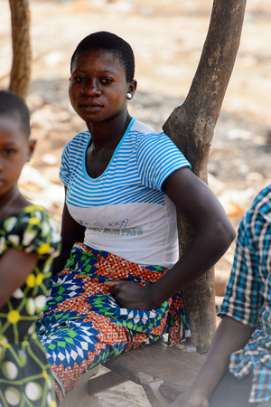 BOHICON, BENIN - JAN 12, 2017: Unidentified Beninese woman in striped shirt sits on the bench at the local market. Benin people suffer of poverty due to the bad economy.のeditorial素材