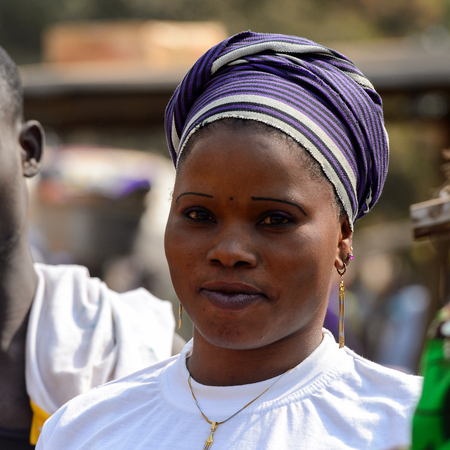 BOHICON, BENIN - JAN 12, 2017: Unidentified Beninese woman in white shirt and purple headscarf looks...